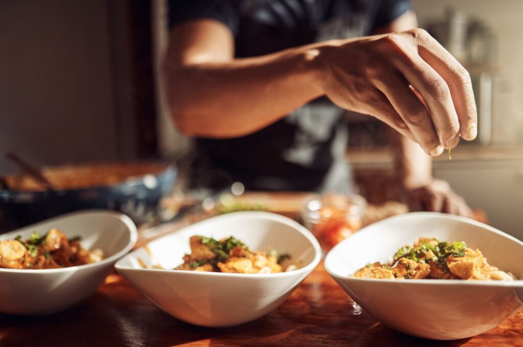 A man adding garnishes to a meal.