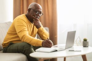 A man writing notes at a coffee table.
